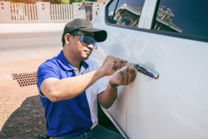 Technician Opening White Car Door With Lockpicker